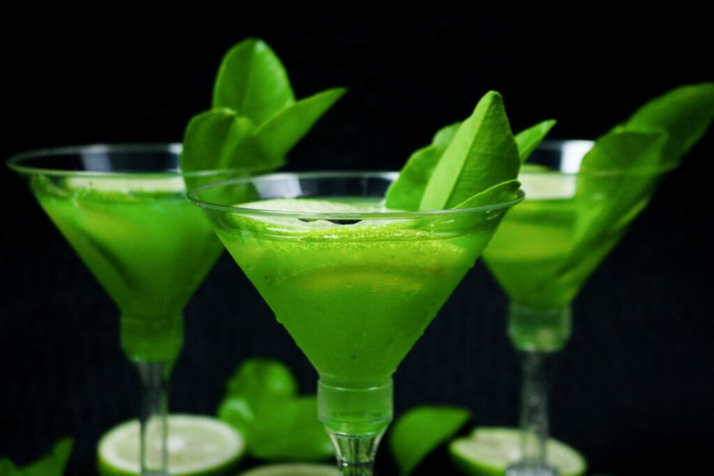 Bright green cocktails garnished with fresh lime and mint leaves, perfect for a refreshing drink.